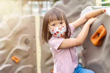 Portrait of young asian girl wearing mask playing outdoor climbing having fun