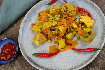 Closeup of isolated china plate with spicy fresh thai fried rice food, carrots, peas, shrimps, chicken, Chillies, maize, eggs seasoned with turmeric on wood table prepared in wok pan