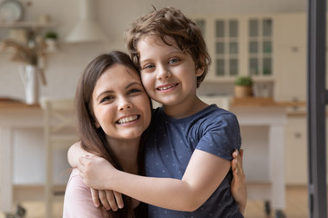 Close up portrait of smiling young mom and little preschooler son embrace look at camera posing at...