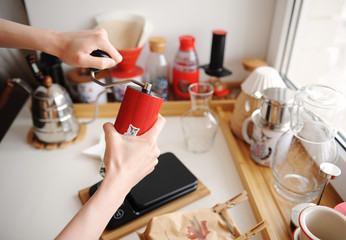 Alternative manual brewing bar. Coffee grinding in red hand grinder. Home barista. Coffee devices in the interior