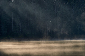 Mist over Blue lake surface at sunrise. Indian Heaven wilderness in Washington state in the USA.