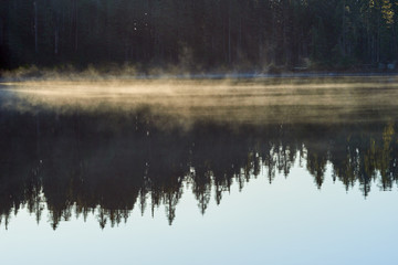 Mist over Blue lake surface at sunrise. Indian Heaven wilderness in Washington state in the USA.