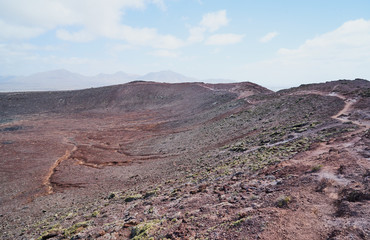 Der Vulkan Montana Roja de Playa Blanca mit einer Höhe von 194m und im Hintergrund die Südwestspitze der Atlantikküste auf der Kanareninsel Lanzarote