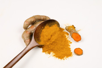 Turmeric powder in a wooden spoon and fresh turmeric roots isolated on a white background is an ingredient in turmeric foods and ingredients in skin care products. Turmeric helps the skin to be strong