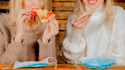 Keep calm and bon appetit! Young bold beautiful women eating pizza without medicine respirator...