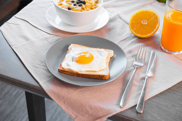 Toast with fried egg, orange juice and bowl with cornflakes, milk and berries on rustic linen tablecloth. Concept of healthy breakfast.