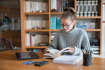 Female caucasian blonde student following an online university lecture from home. Isolation during the coronavirus period