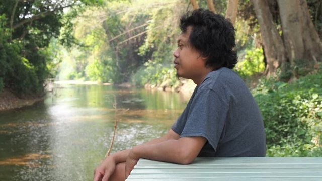 Asian handsome man is sitting and smoking in the forest.