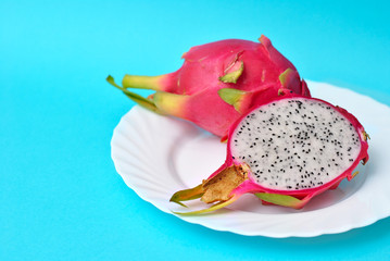 Close up view of exotic dragon fruit cut and whole sliced isolated on a blue background.