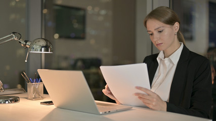 The Ambitious Businesswoman Reading Document on Office Desk at Night