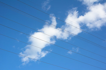 Fototapeta premium Electric wire and overhead power line. Clear blue sky with white cloud as background.
