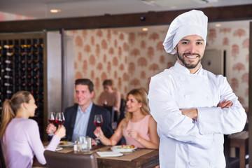 Confident smiling chef standing in restaurant hall