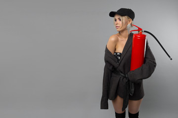 beautiful young girl in a cap with a fire extinguisher in her hands.Fire safety. woman holding a fire extinguisher