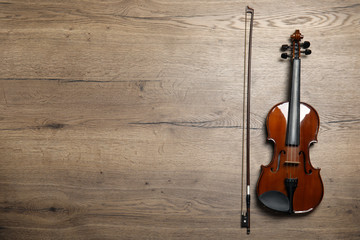 Fototapeta na wymiar Classic violin and bow on wooden background, flat lay. Space for text