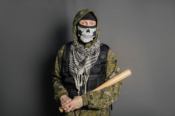 Unknown man, a robber in a balaclava with a skull, in camouflage uniform and body armor with a...