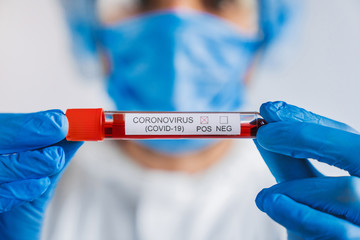 Close up of young male scientist holding test tube with blood sample for coronavirus positive research at clinical laboratory