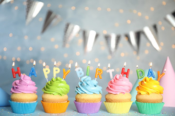 Birthday cupcakes with burning candles on grey table