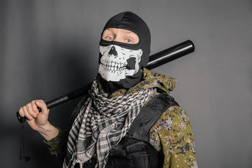 Unknown man, a robber in a balaclava with a skull, in camouflage uniform and body armor with a...