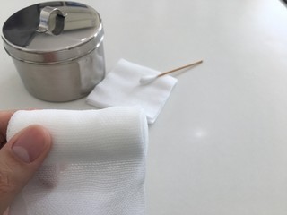 Fototapeta na wymiar finger tip hold roll gauze on blur swab and gauze jar in medical concept