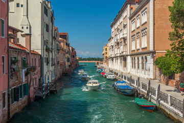 Fototapeta na wymiar View of narrow Canal with boats and gondolas in Venice, Italy