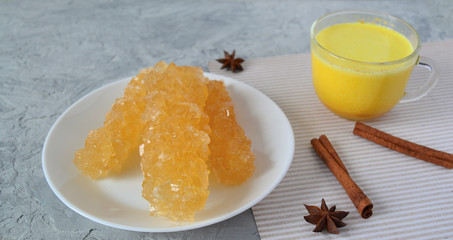 Uzbek sugar Navat. Oriental sweets with turmeric milk on gray concrete table background. Ramadan drink.