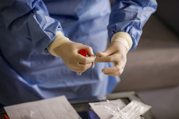 Details with the hands of a medic using a coronavirus test on a person.