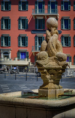Fototapeta na wymiar A dolphin fountain with old traditional houses in the background in Old Town Vielle Ville in Nice in the South of France