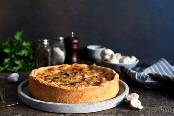 Quiche with chicken, mushrooms and cheese on a dark concrete background. Just on the kitchen table.