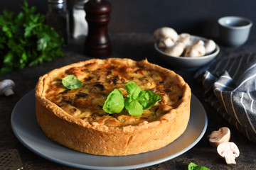 Quiche with chicken, mushrooms and cheese on a dark concrete background. Just on the kitchen table.