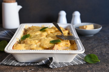 Casserole with potatoes, mushrooms and cheese on the kitchen table. Horizontal focus.