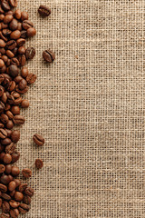 roasted coffee beans on the edge of a burlap surface