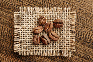 coffee beans on a burlap flap close-up on a background of rough wood.