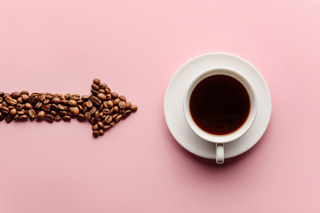 An arrow lined with coffee beans indicates a nearby cup of coffee. Coffee love concept on a pink...