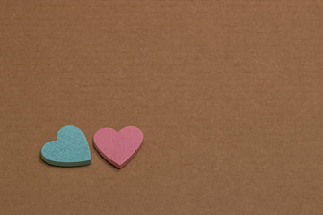 A blue and pink decorative heart lies on brown cardboard. Symbol of masculine and feminine. The problem of recycling paper and raw materials.