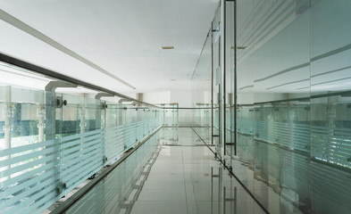 Walk way decorated with glass and mirros shows the reflection and modern office style.