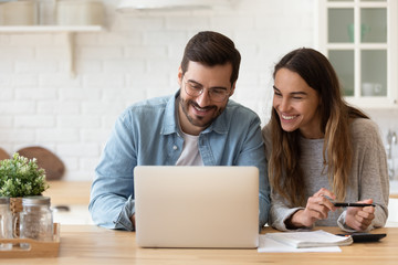 Happy young couple planning budget, reading good news in email, refund or mortgage approval,...