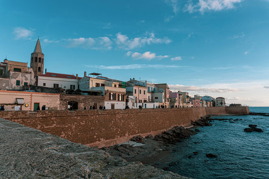 Alghero old town seafront with bastions and cathedral bell tower, Sardinia