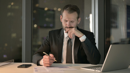 The Young Businessman Thinking and writing Document at Night