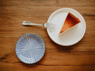 Basque Burnt Cheesecake on plate with piece of cake on wooden table