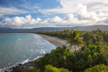 Four Mile Beach lookout at Port Douglas, Queensland, Australia. Sun highlights the palm trees at the beach with blue and cloudy sky.