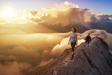 Girl Hiking on a mountain with Beautiful and striking view of the puffy clouds during a colorful and vibrant sunset or sunrise. Nature Background. Concept: Freedom, Lifestyle, Adventure, Hike, Explore