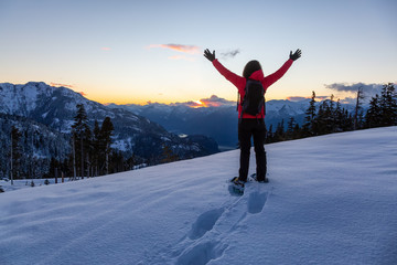 Fototapeta na wymiar Adventurous Girl Snowshoeing in the snow on top of a mountain during a vibrant and colorful winter sunset. Taken on Anif Peak, Squamish, British Columbia, Canada. Concept: explore, adventure