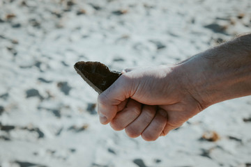 a pointed stone knife of ancient hunters in a man’s hand
