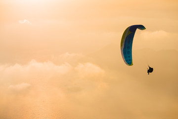 The beauty of paragliding. Extreme sport. Romance of heights. Landscape at sunset. Flying above the clouds.