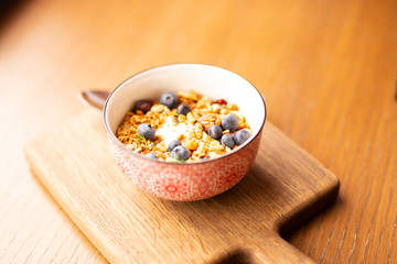 Fototapeta na wymiar Homemade granola bowl with greek yogurt and blueberries on brown background, top view. Healthy energy breakfast or snack