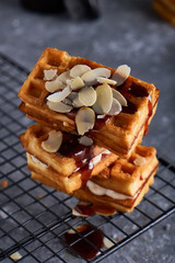 delicious homemade Vienna waffles with syrup and almond crumbs served on a gray table