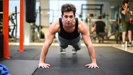 Obraz na płótnie Canvas Man doing push ups in a gym