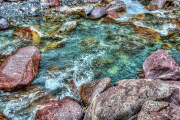 clear and pure water stream in the swiss Alps with colorful stones 