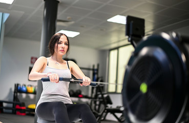 Obraz premium Young woman working out on the rowing machine