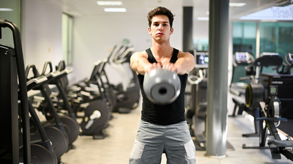 Man training in a gym using a kettlebell